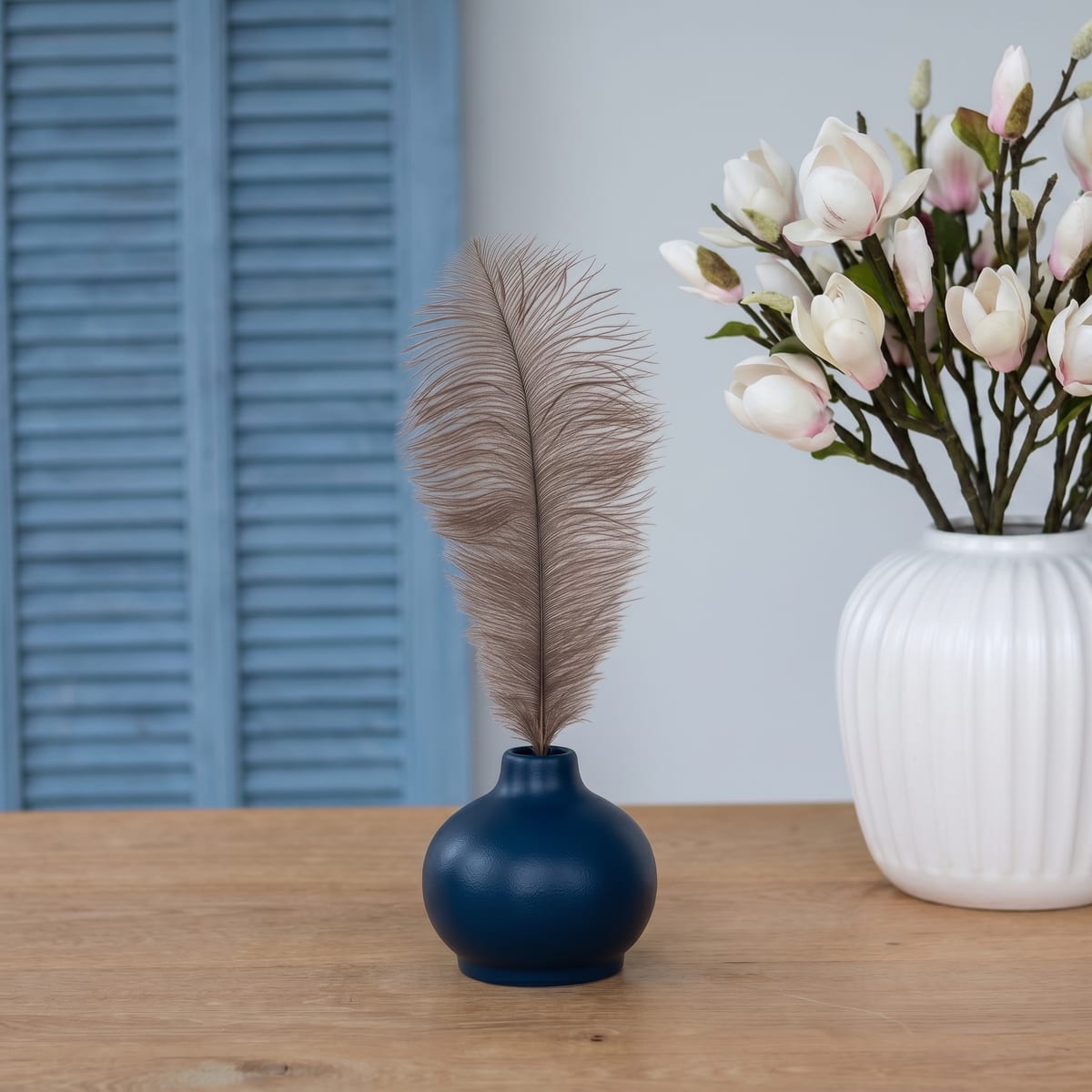 The navy blue vase on an oak table, beside white magnolias and pale blue shutters